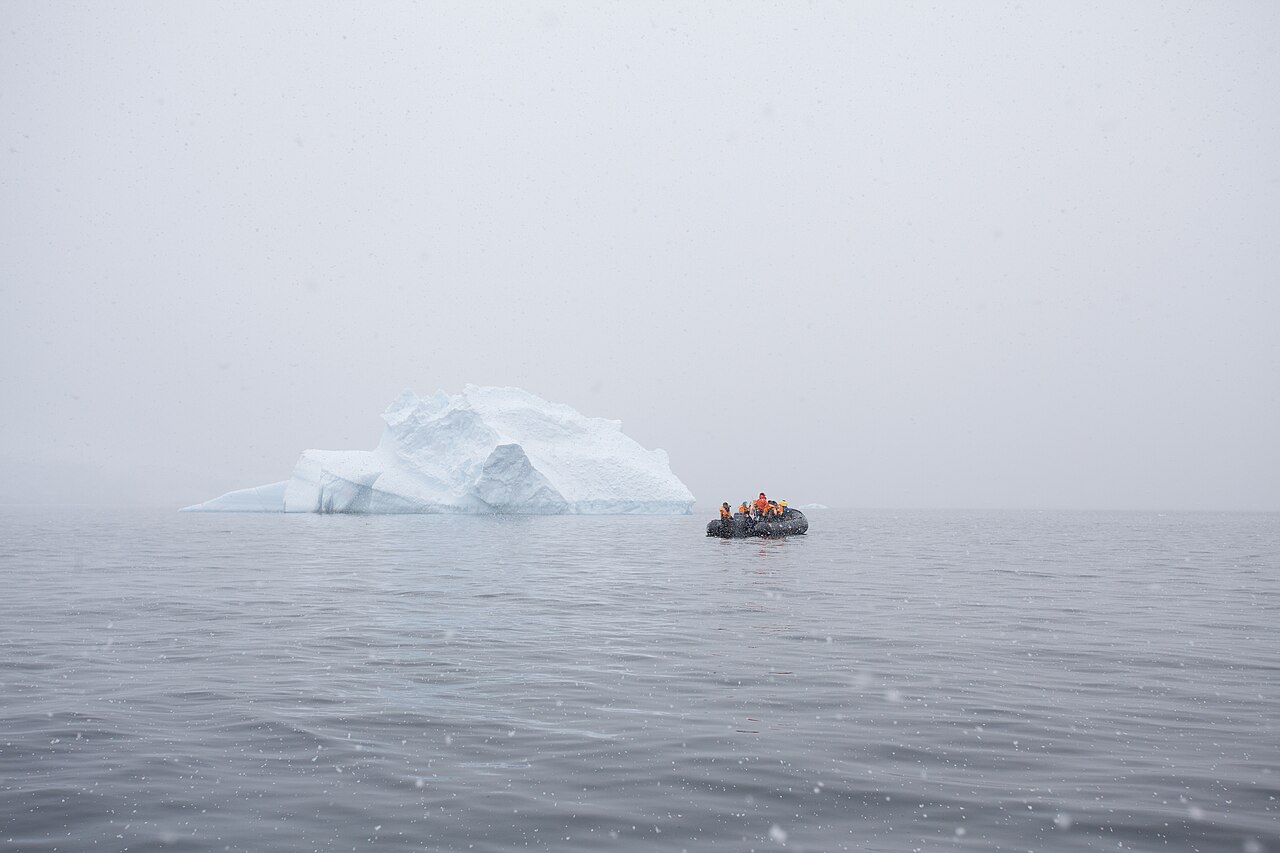 Zodiac boat with passengers passing a small iceberg
